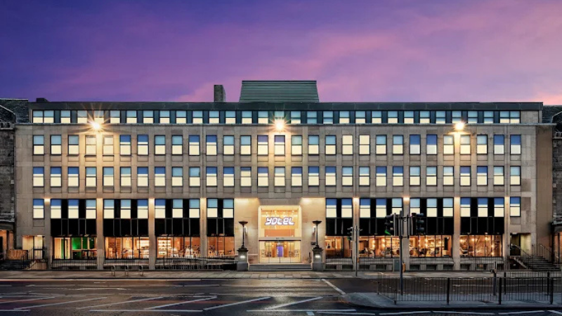 Fasad av YOTEL Edinburgh vid skymning med upplysta f�nster och entr�, centralt bel�get hotell n�ra Princes Street i Edinburgh.